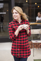 a young woman in a plaid shirt holding a coffee cup 