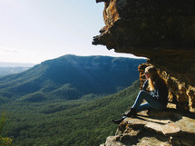 woman sitting on the edge of a mountain 