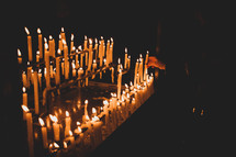Candle flames in the church. Dark mood with burnt candles.