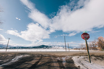 stop sign and snow on a dirt road 