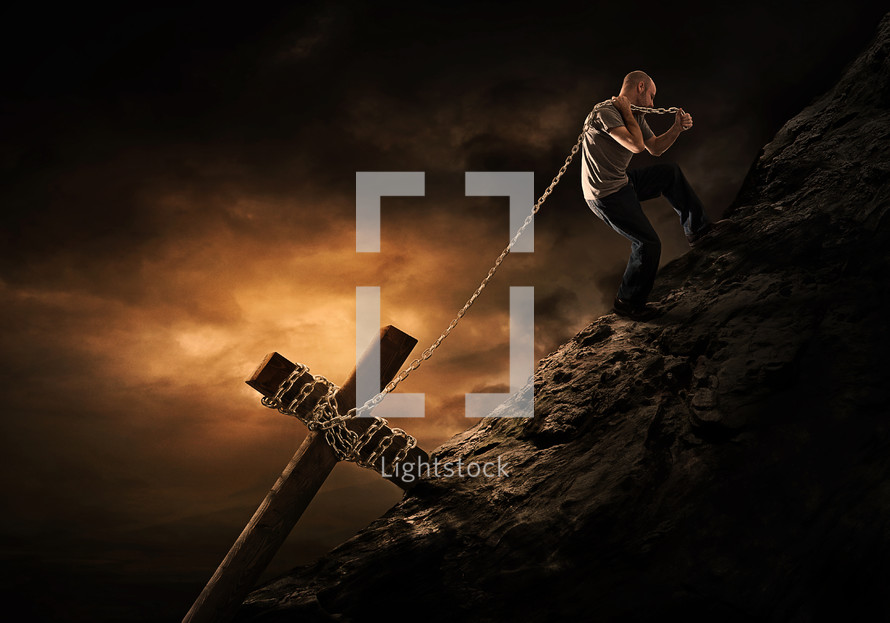 a man lifting a cross wrapped in a chain up a mountain 