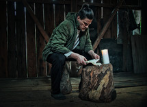 man reading a Bible in a barn by candlelight 