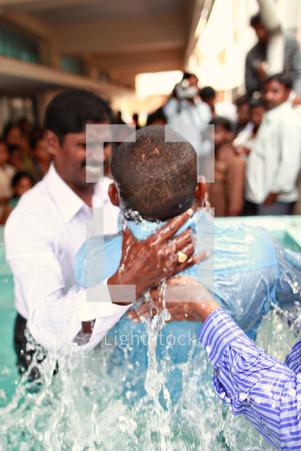 man being dunked during a baptism in India