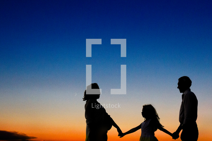 silhouette of a family holding hands at sunset