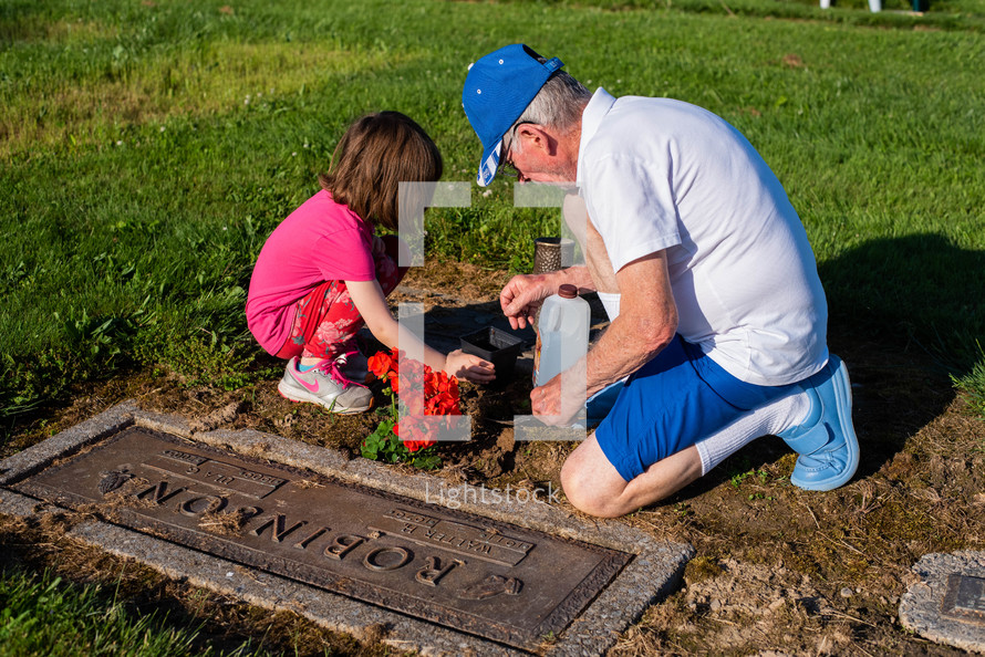 a granddaughter and grandfather spending time at a cemetery 