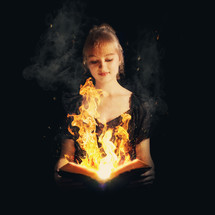 Girl holding an open Bible with flames emerging from the center of the pages.