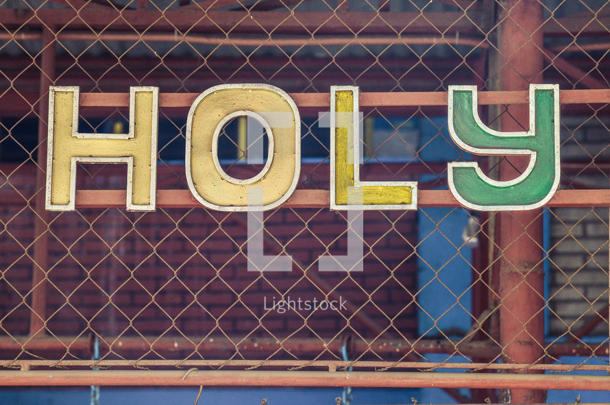 word Holy on a chain link fence 
