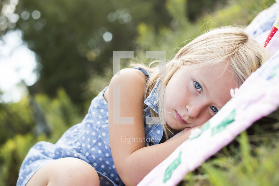 girl child lying on a blanket in the grass 