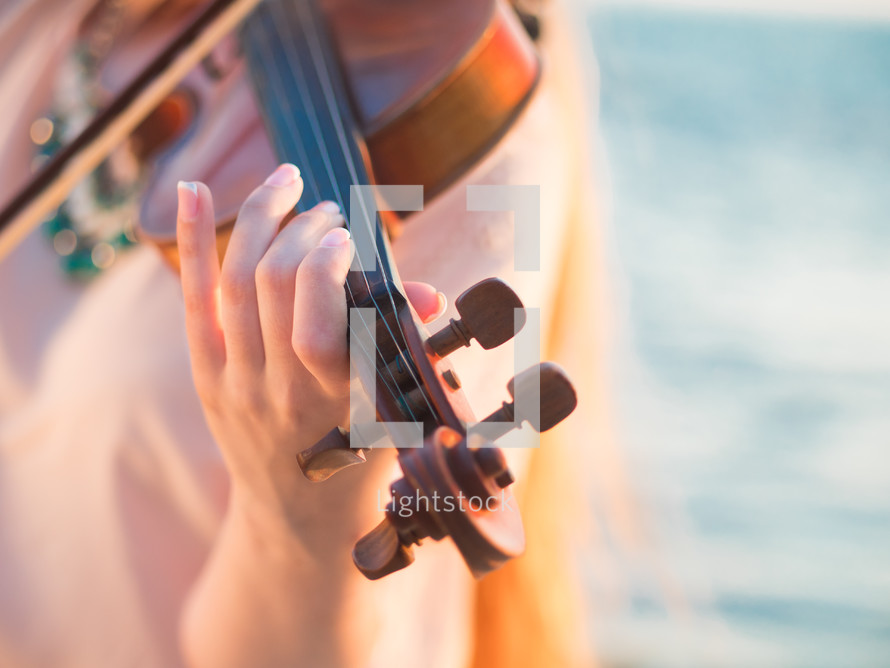 Young woman playing a violin on the beach.