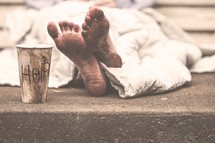 A woman sleeping on the ground with a help cup 