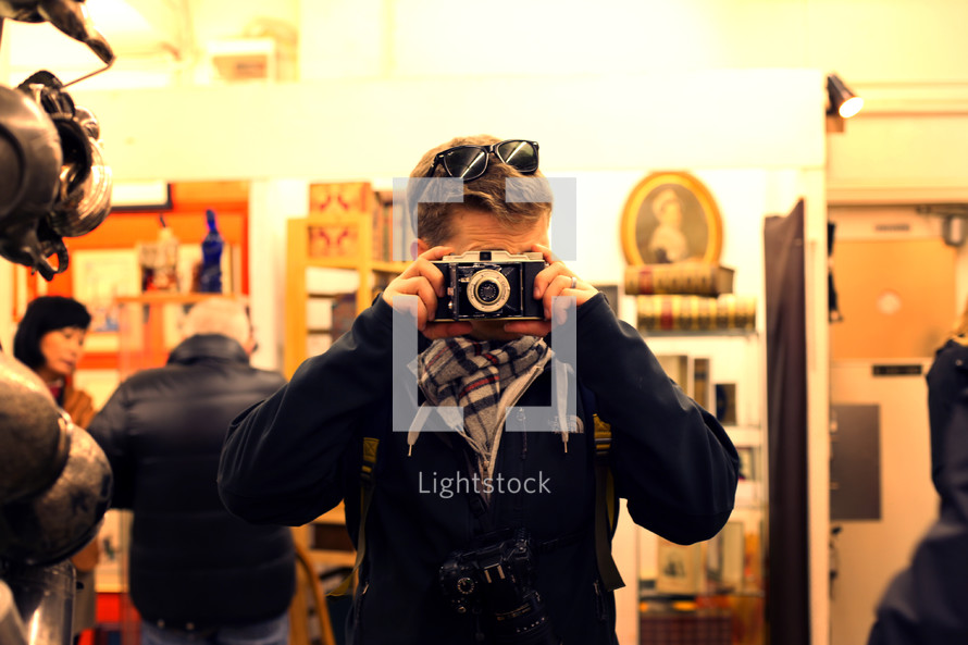 man taking a picture in an antique market with a camera 