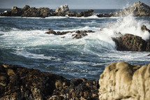 waves crashing into rocks along a shore 