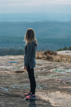 a woman standing on a mountaintop taking in the view 