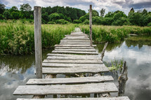 old weathered and broken foot bridge across water 