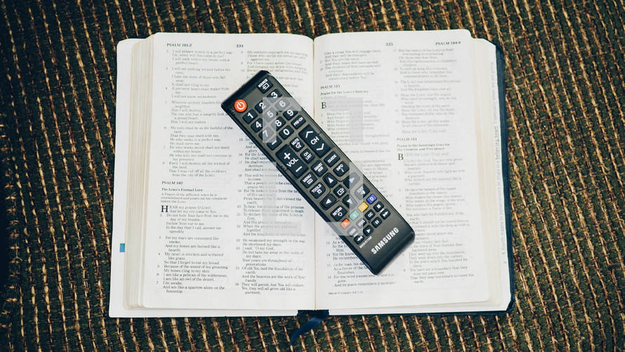 remote control on the pages of a Bible 