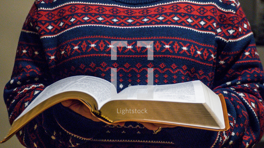 a woman reading a Bible in a sweater 