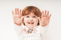 a toddler with her hands up 