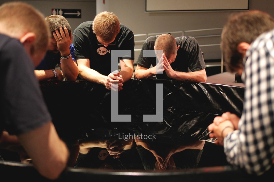 Young men sitting and praying together.