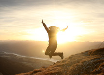 woman jumping for joy on a mountain top 