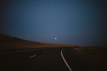 moon over a curve in a road