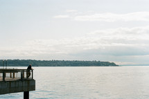 a man standing on a pier looking out at the water 