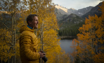 man with a camera standing by a lake in fall 