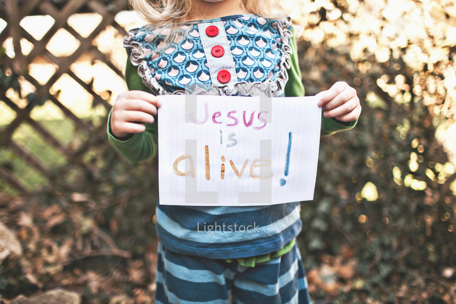 girl holding a sign that says "Jesus is Alive" 