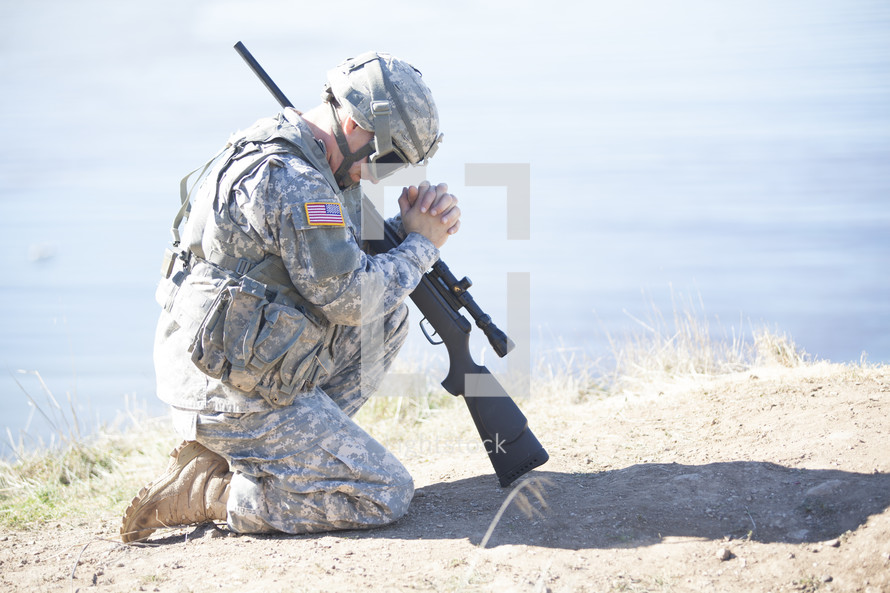 soldier with a rifle kneeling in prayer to God