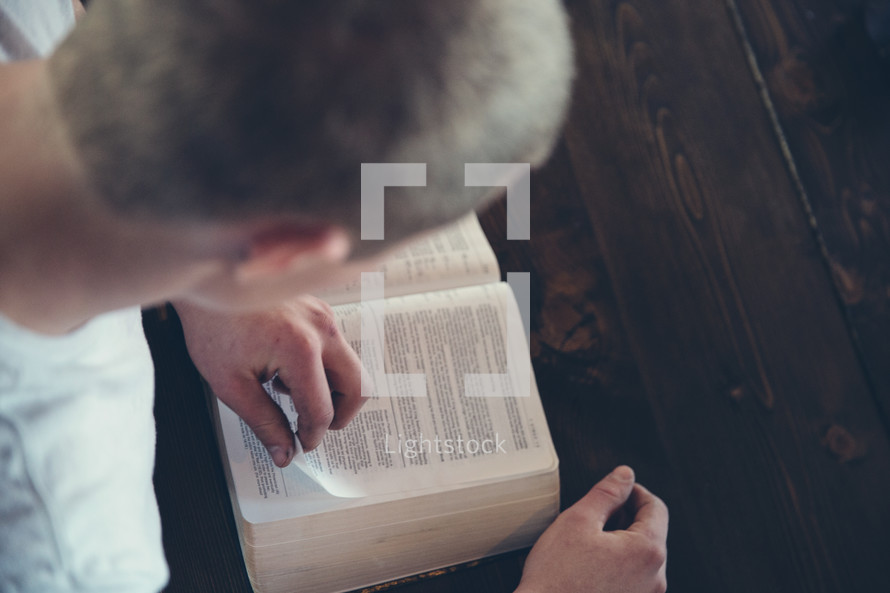 Young man flipping through the pages of a Bible. 