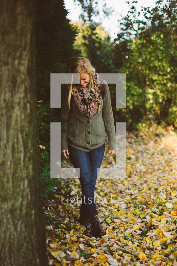 a woman walking in fall leaves 