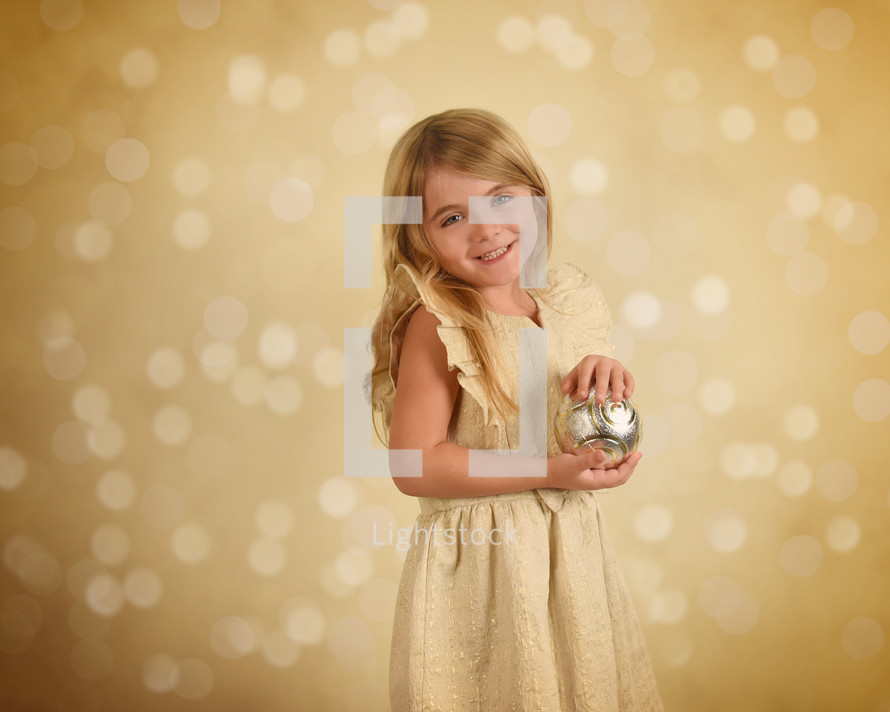 A light girl holding a Christmas ornament 
