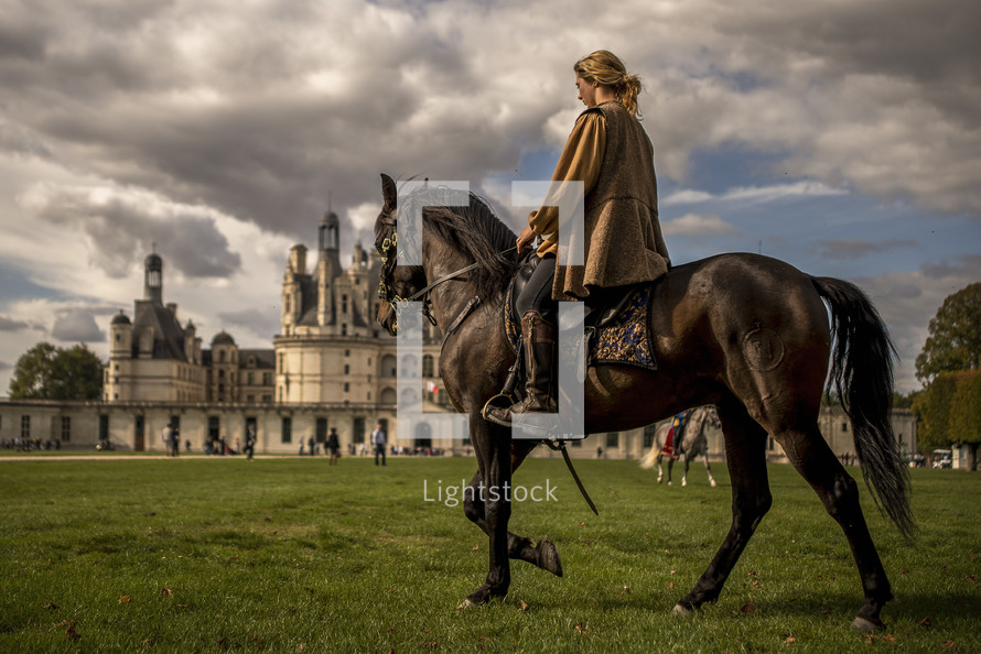 a woman riding a horse near a castle 
