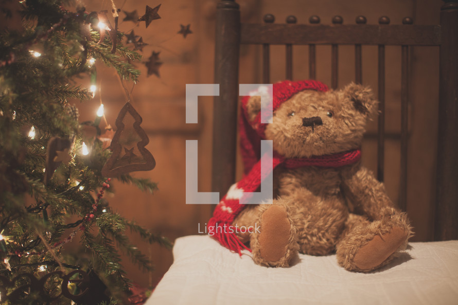 a holiday bear on a table and Christmas tree