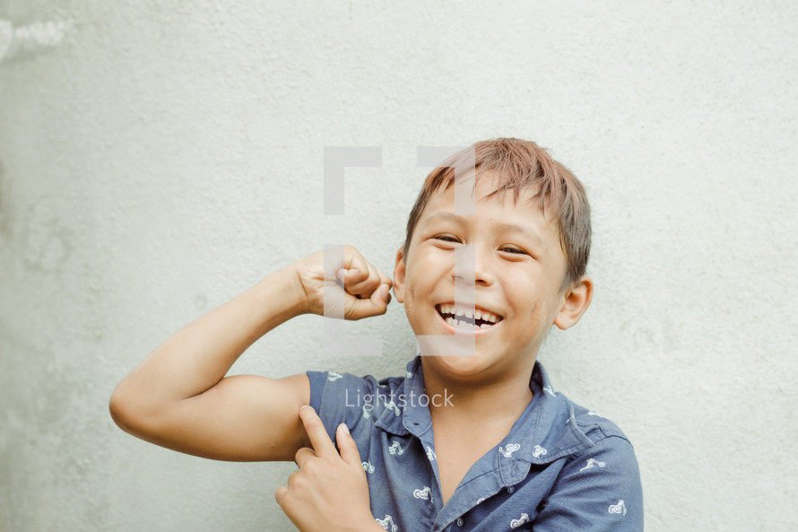 smiling child showing his muscles 
