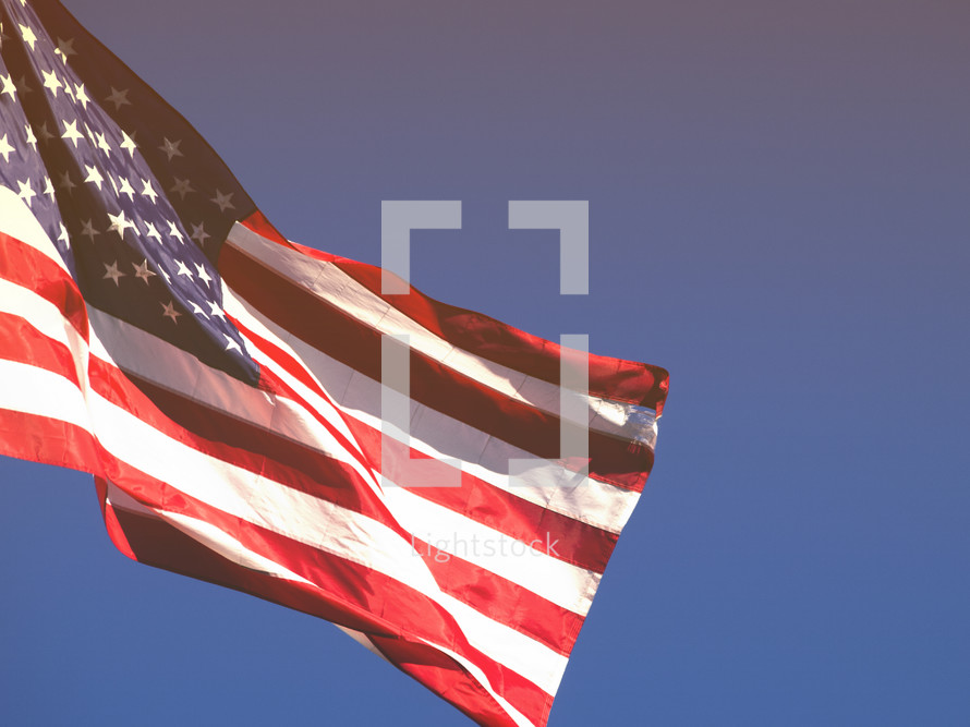 An American flag fluttering against a blue sky.