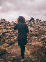 a woman hiking up a rugged mountainside 