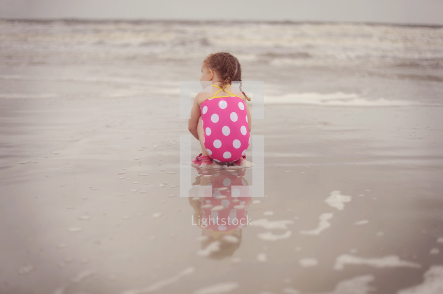 a child sitting on wet sand 