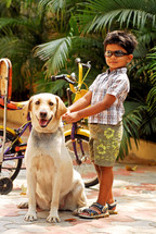 a child with a bike petting a dog 