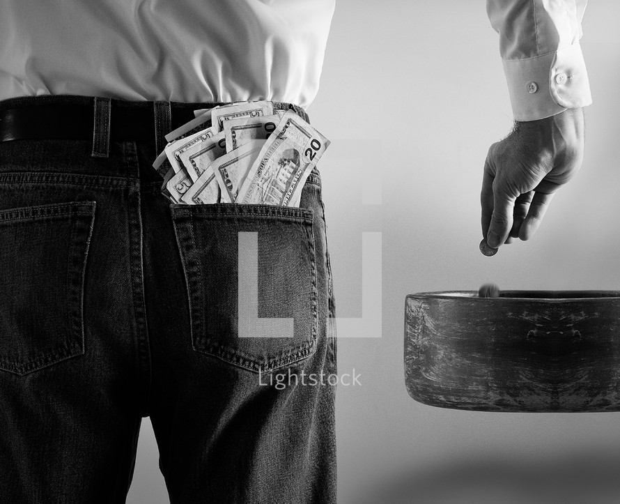 man with cash in his pocket dropping pennies in a tithe bowl 