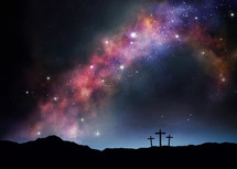 Three crosses on a hill under the starry night sky.