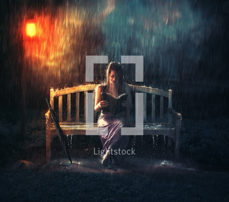 woman sitting on a bench reading a Bible in the rain 