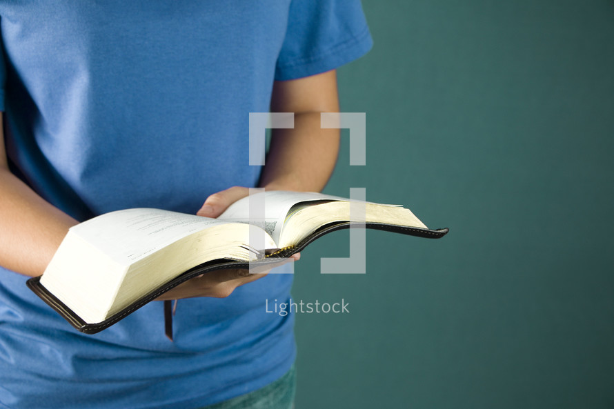A young person holds her Bible opened to read