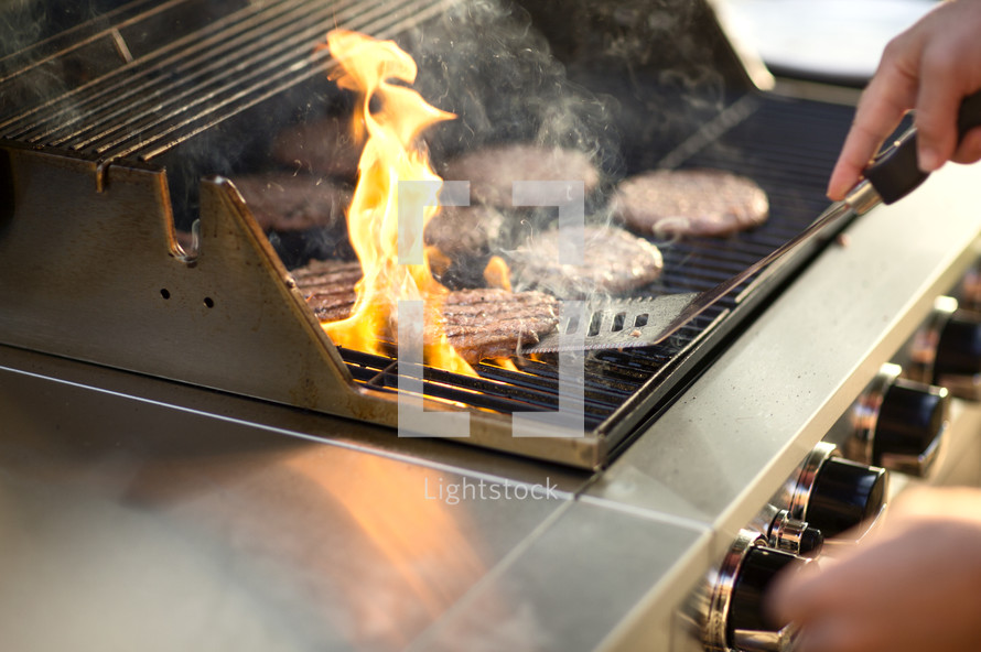 a man cooking hamburgers on the grill 