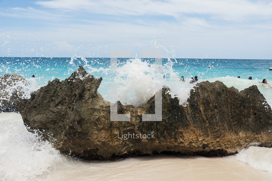 Ocean waves splashing on a rock on the beach.