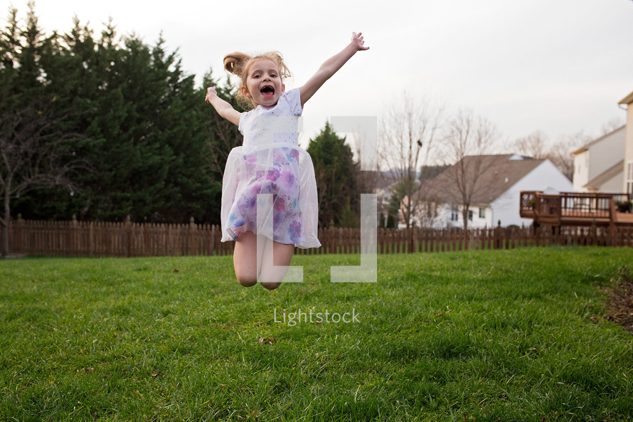 a girl jumping up in the backyard 