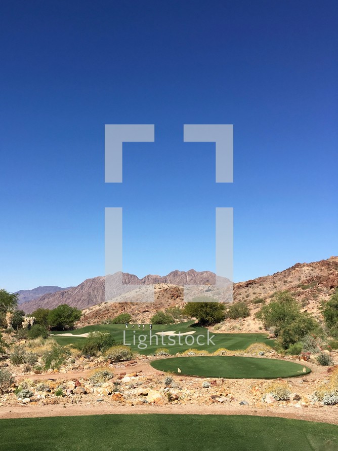 golfers on a golf course surrounded by desert mountains in Nevada 