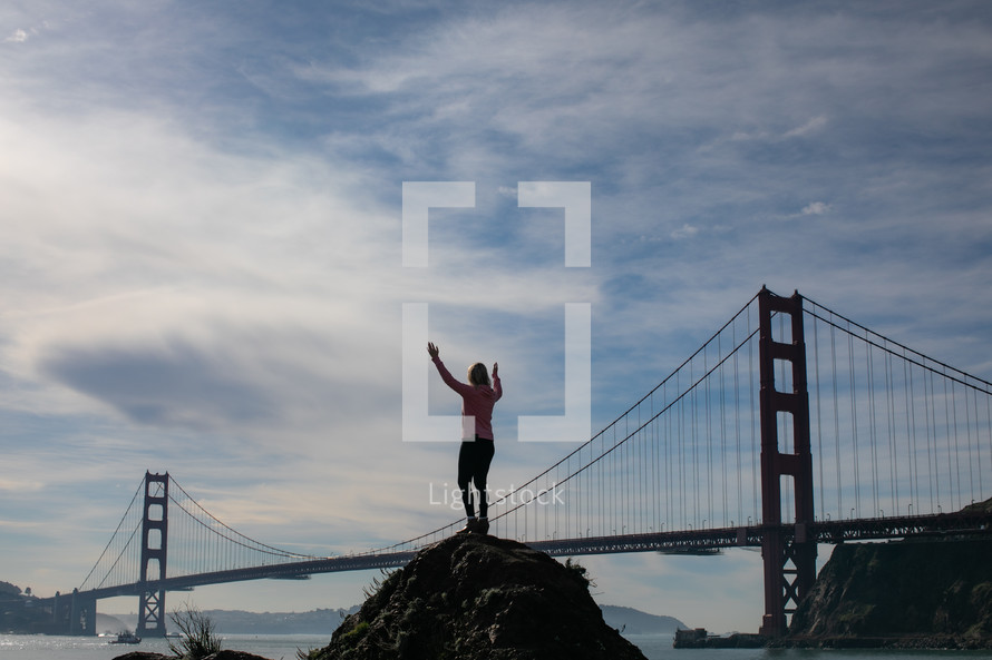 person standing with outstretched arms and Golden Gate Bridge in the background 