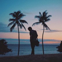 silhouette of a man on a beach and palm trees 