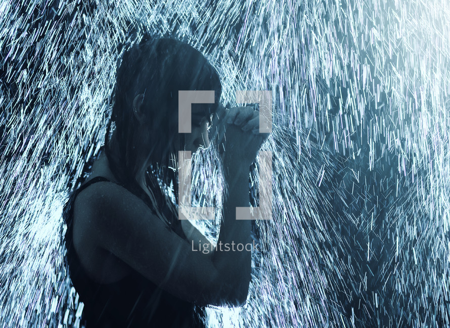 a woman praying under falling rain 