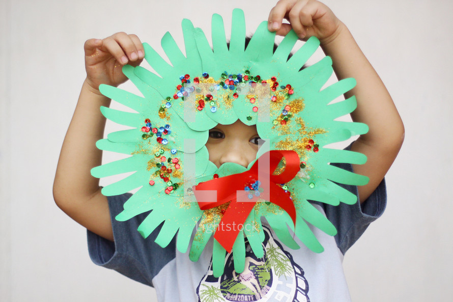 a child holding a handmade wreath 